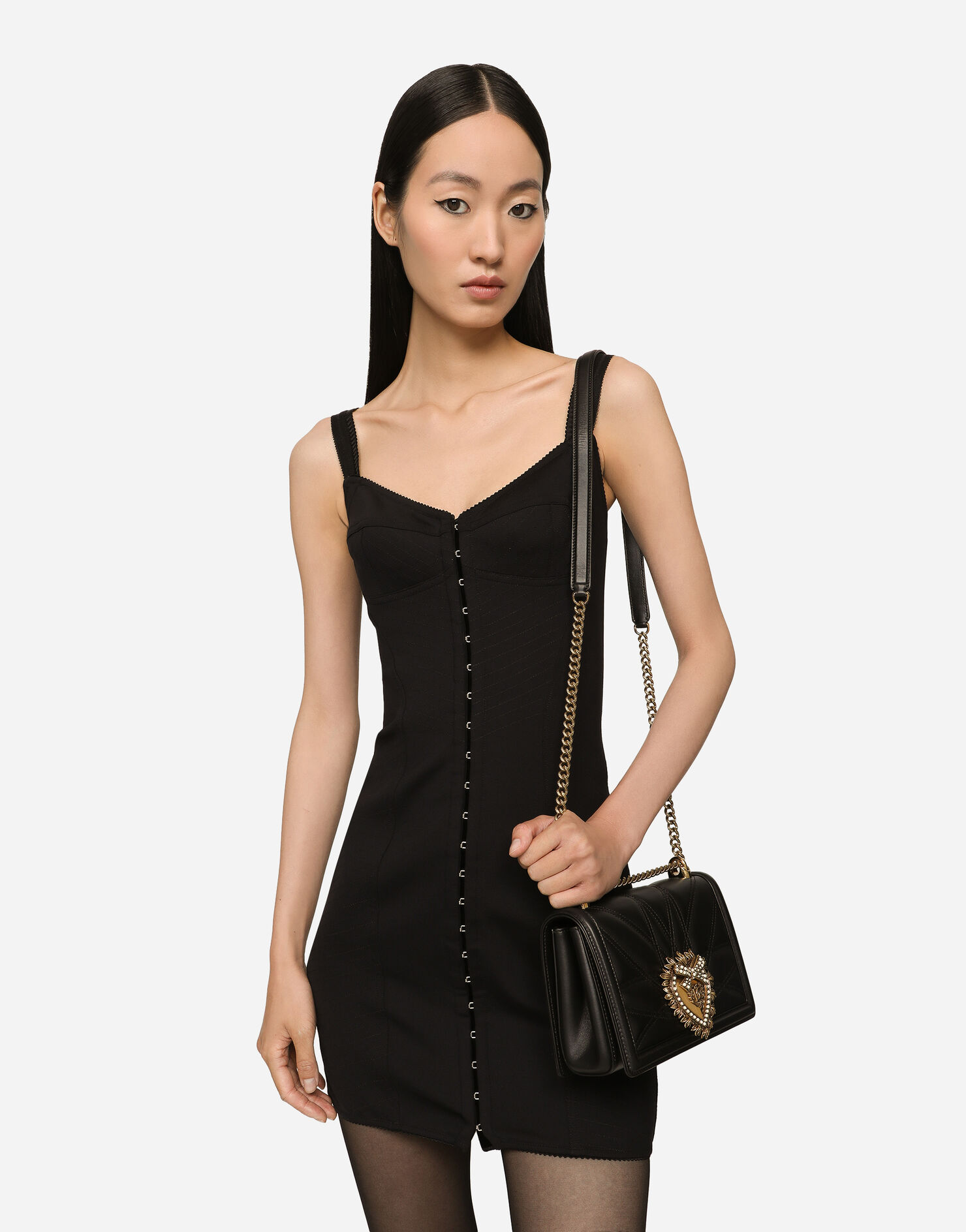 Model wearing a black Dolce & Gabbana Devotion bag with a fitted black dress.